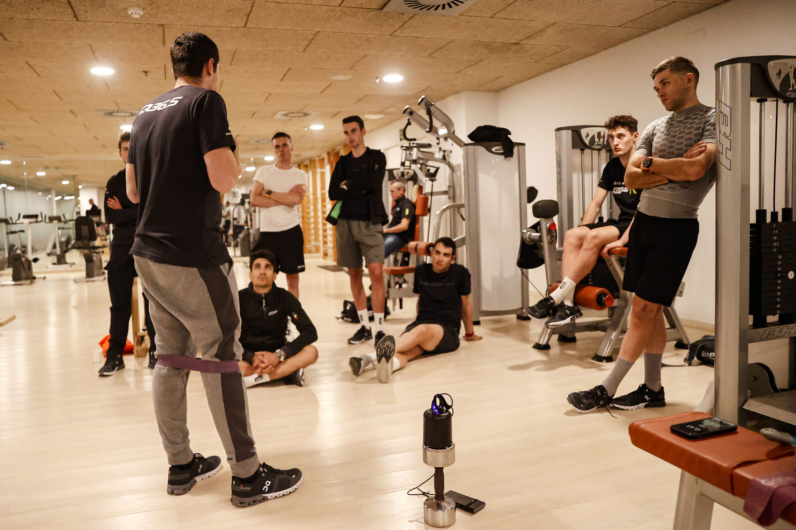 Carles Tur, Head Coach of Q36.5 Pro Cycling Team, briefing a group of cyclists in the gym before a workout session.