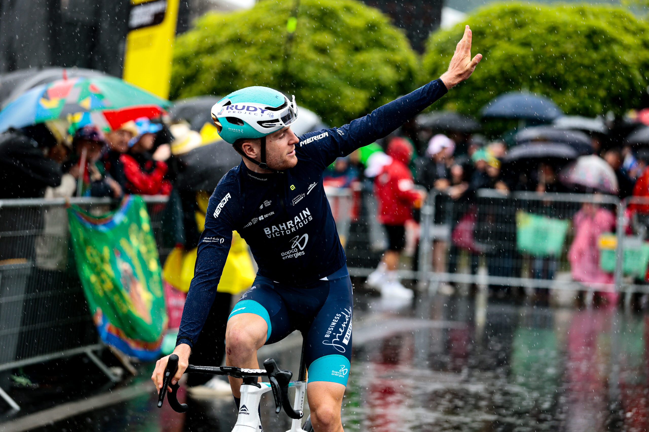 Fred Wright of Bahrain-Victorious waves to fans in the rain during Stage 2 of the 2025 Tour de France.